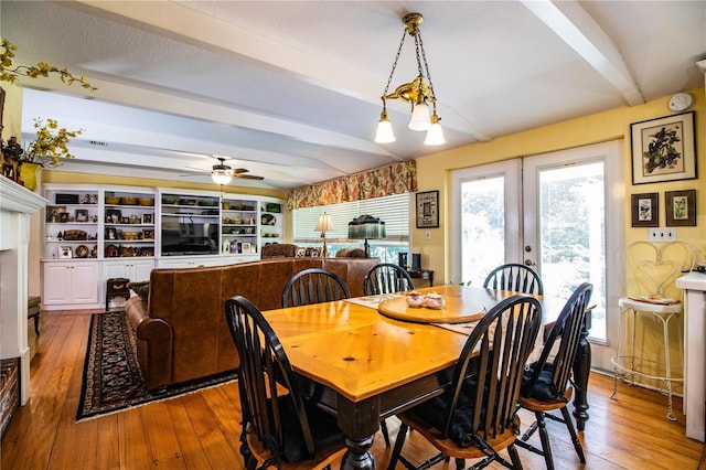 dining room featuring beam ceiling, ceiling fan with notable chandelier, hardwood / wood-style flooring, and french doors