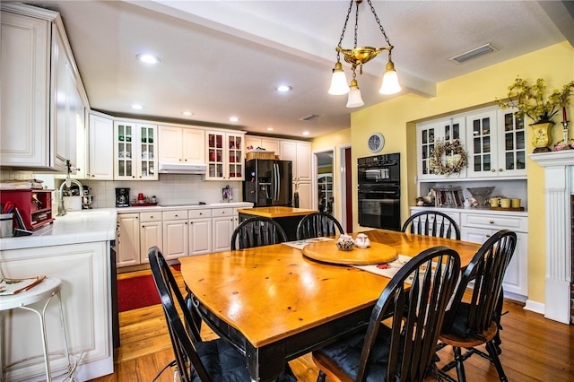 dining space with beamed ceiling, an inviting chandelier, dark wood-type flooring, and sink