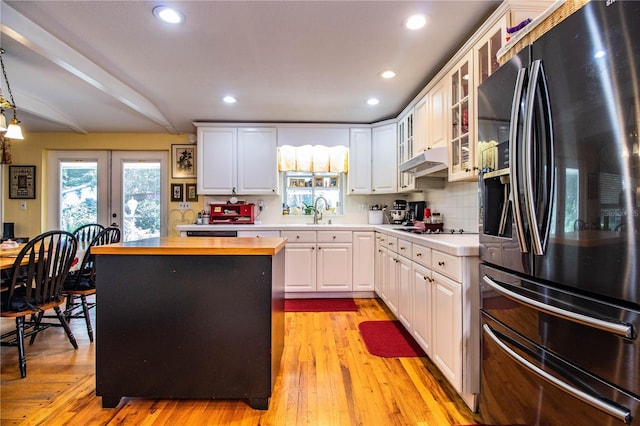 kitchen with black appliances, decorative light fixtures, white cabinets, and butcher block counters