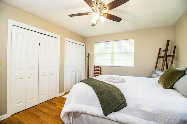 bedroom featuring ceiling fan, two closets, and hardwood / wood-style flooring