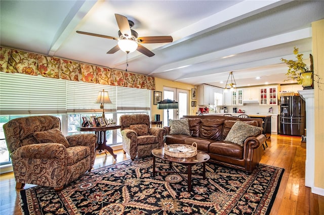 living room featuring beam ceiling, light hardwood / wood-style floors, and ceiling fan