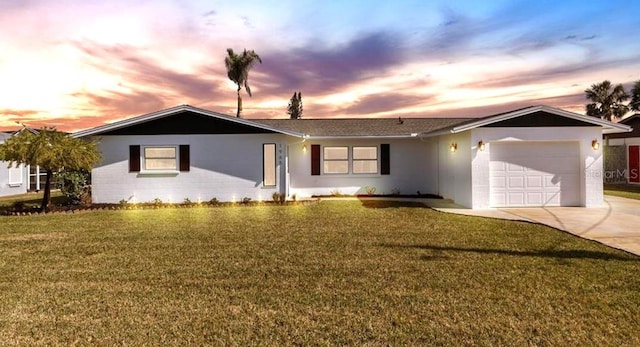 ranch-style home featuring a garage and a lawn