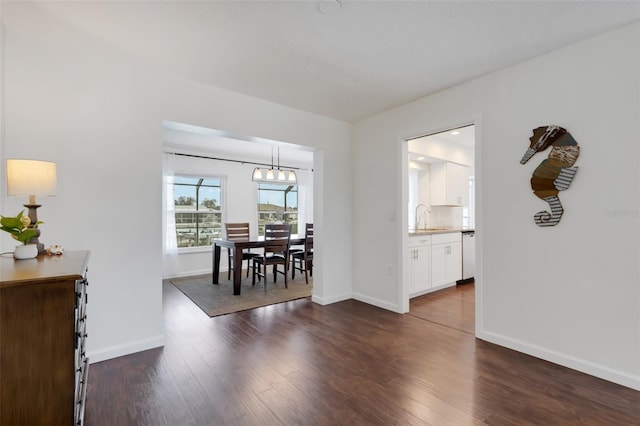 dining space featuring sink, dark wood-type flooring, and a chandelier