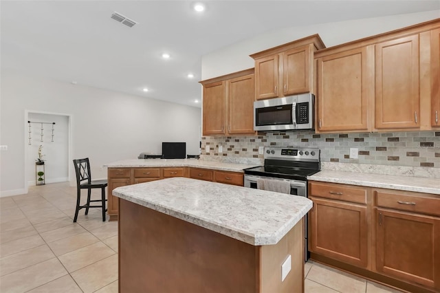 kitchen featuring appliances with stainless steel finishes, backsplash, a center island, and light tile patterned floors