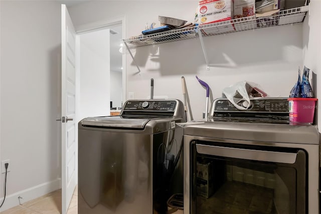 clothes washing area with light tile patterned floors and washer and clothes dryer