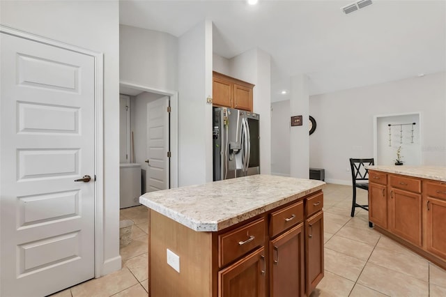 kitchen featuring stainless steel refrigerator with ice dispenser, light tile patterned flooring, and a kitchen island