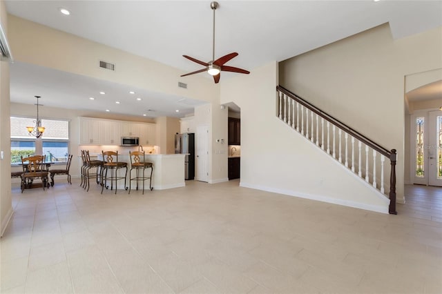 living room with ceiling fan with notable chandelier and a towering ceiling