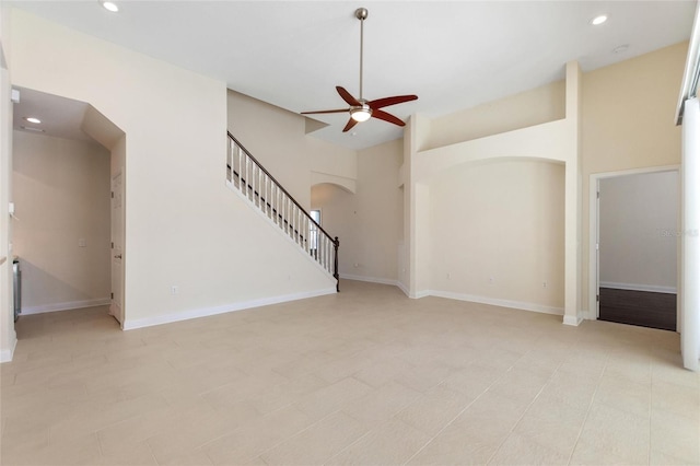 unfurnished living room featuring ceiling fan and a towering ceiling