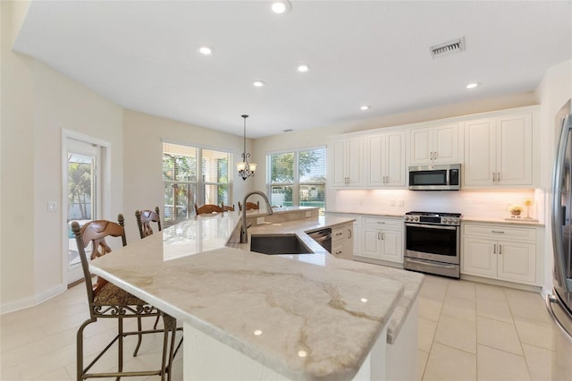 kitchen with stainless steel appliances, decorative light fixtures, a kitchen breakfast bar, and a spacious island