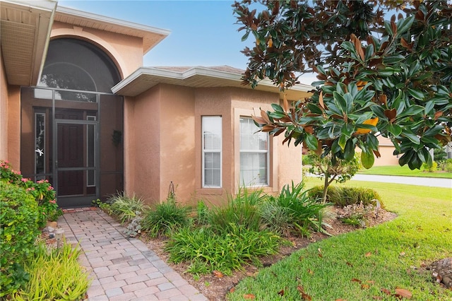 view of exterior entry with a yard