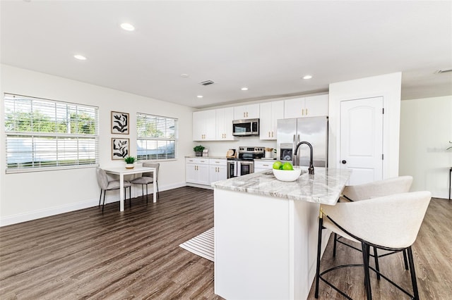 4618 Crestview Ln, Lakeland, FL 33813 - kitchen with appliances with stainless steel finishes, dark wood-type flooring, white cabinetry, light stone countertops, and a kitchen breakfast bar