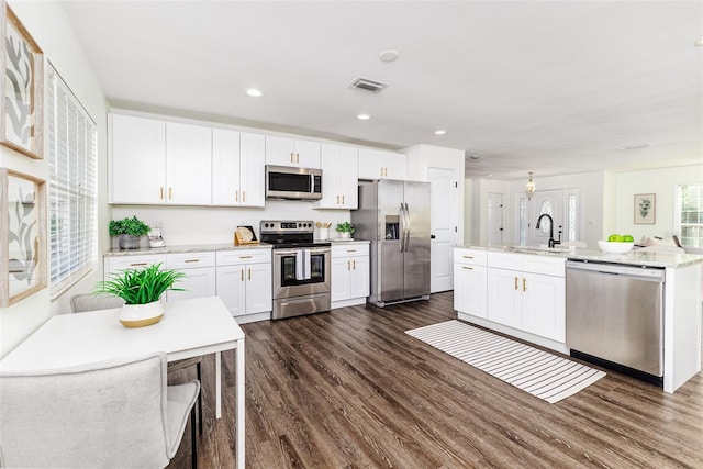 4618 Crestview Ln, Lakeland, FL 33813 - kitchen featuring stainless steel appliances, dark wood-style flooring, white cabinets, a center island with sink, and recessed lighting