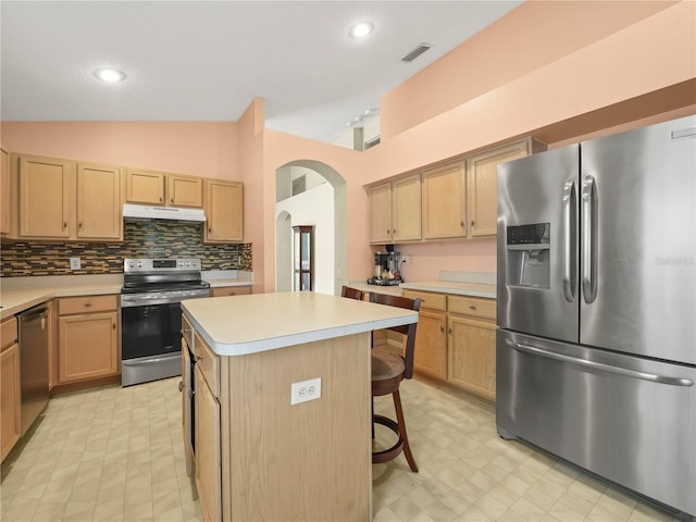 kitchen with lofted ceiling, a kitchen island, stainless steel appliances, a breakfast bar area, and decorative backsplash