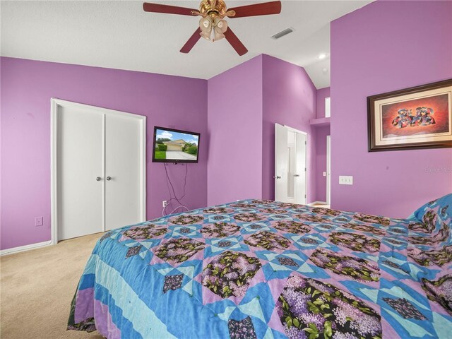 bedroom featuring a closet, lofted ceiling, ceiling fan, and light colored carpet