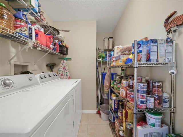 laundry area featuring a textured ceiling, washer and clothes dryer, and light tile patterned floors