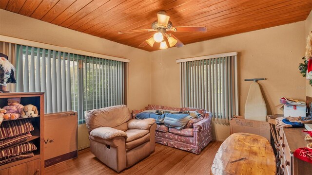 living room featuring ceiling fan, light wood-type flooring, and wooden ceiling