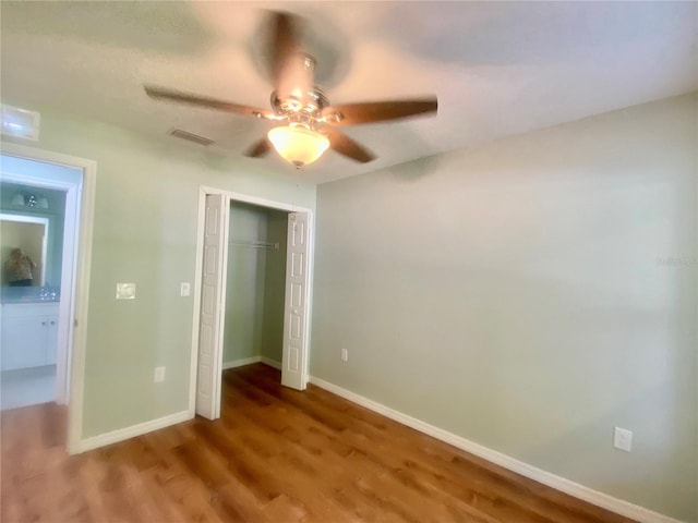 unfurnished bedroom featuring visible vents, baseboards, ceiling fan, wood finished floors, and a closet