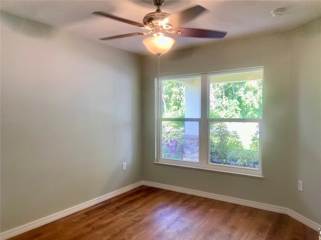 unfurnished room with wood finished floors, a ceiling fan, and baseboards