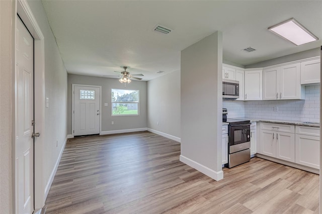 kitchen with stainless steel appliances, white cabinets, ceiling fan, and light wood-type flooring