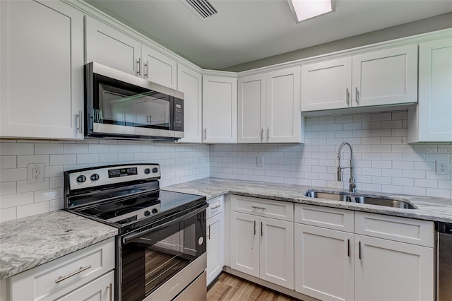 kitchen featuring stainless steel appliances, white cabinets, light wood-type flooring, and sink