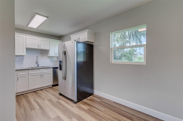 kitchen featuring light hardwood / wood-style floors, white cabinetry, backsplash, stainless steel appliances, and sink