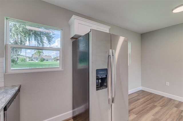 kitchen with light hardwood / wood-style floors, white cabinets, stainless steel appliances, and a wealth of natural light