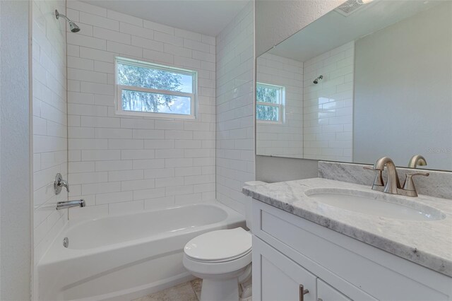 full bathroom featuring vanity, tiled shower / bath combo, and toilet