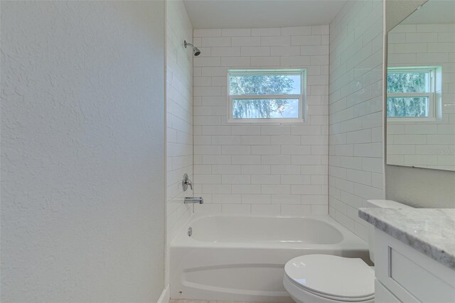 full bathroom with tiled shower / bath, vanity, toilet, and plenty of natural light