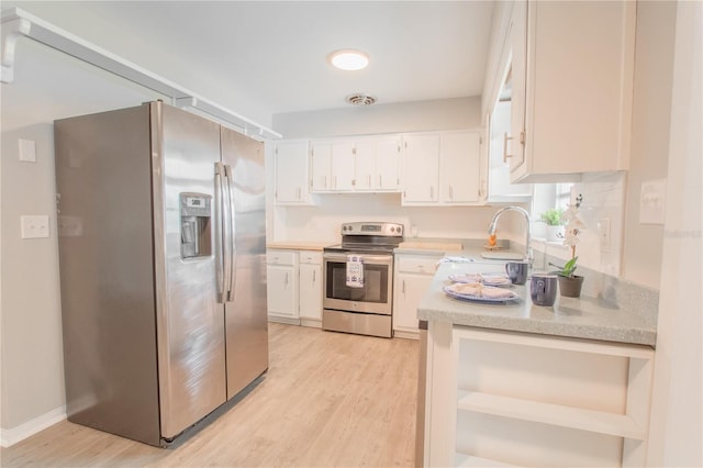 kitchen with stainless steel appliances, white cabinets, light wood-type flooring, and sink