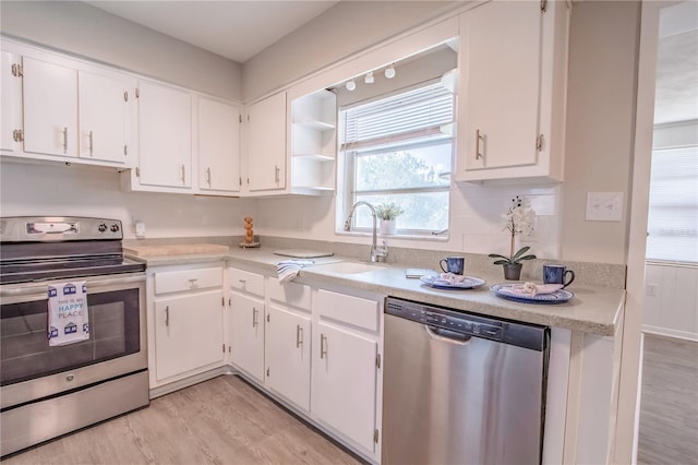 kitchen with light wood-type flooring, sink, white cabinetry, stainless steel appliances, and backsplash