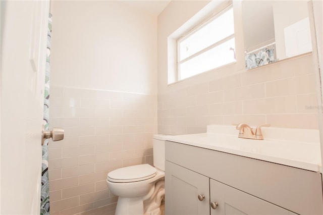 bathroom with tile walls, vanity, and toilet