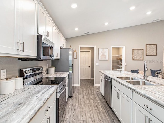 kitchen featuring white cabinetry, stainless steel appliances, light wood-type flooring, lofted ceiling, and sink