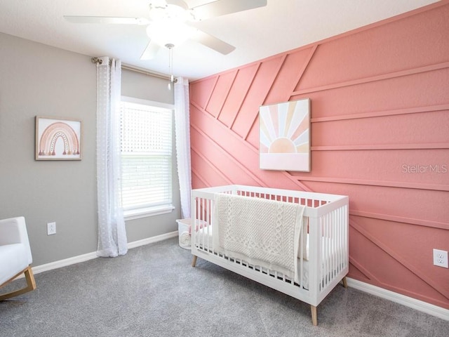 unfurnished bedroom featuring ceiling fan, a crib, wood walls, and carpet flooring