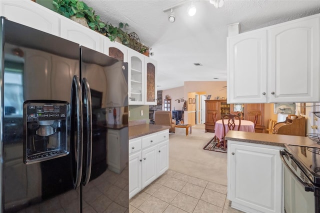 kitchen featuring white cabinetry, black fridge, and light tile patterned flooring