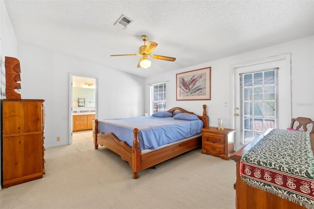 bedroom with light carpet, connected bathroom, ceiling fan, and a textured ceiling