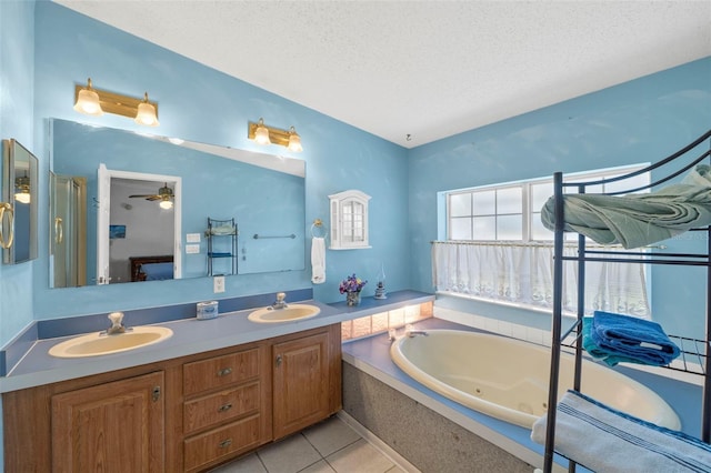 bathroom featuring ceiling fan, vanity, a relaxing tiled tub, a textured ceiling, and tile patterned flooring