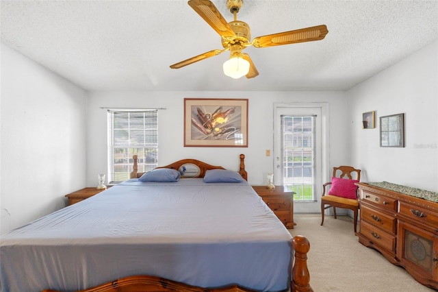 bedroom with light carpet, ceiling fan, multiple windows, and a textured ceiling