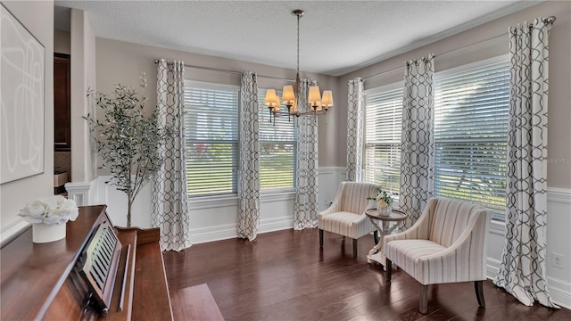 sitting room with an inviting chandelier, a textured ceiling, and dark hardwood / wood-style flooring