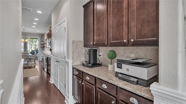 kitchen featuring dark brown cabinetry, a chandelier, light stone countertops, dark hardwood / wood-style flooring, and decorative backsplash