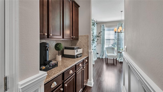 kitchen featuring dark brown cabinetry, pendant lighting, an inviting chandelier, tile walls, and dark hardwood / wood-style flooring