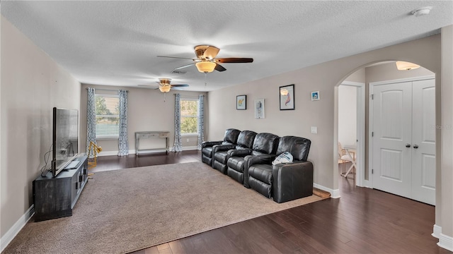 living room with ceiling fan, a textured ceiling, and dark hardwood / wood-style floors