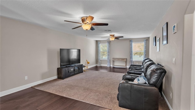 living room with a textured ceiling, ceiling fan, and dark wood-type flooring