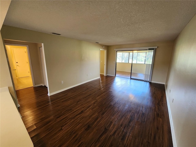 empty room featuring a textured ceiling and dark hardwood / wood-style flooring