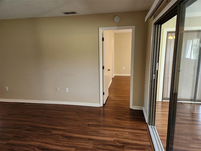 hallway with a textured ceiling and dark wood-type flooring