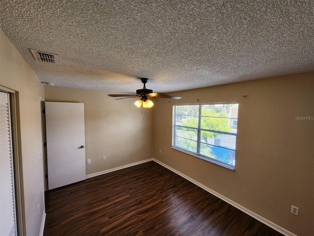 unfurnished room with a textured ceiling, dark wood-type flooring, and ceiling fan