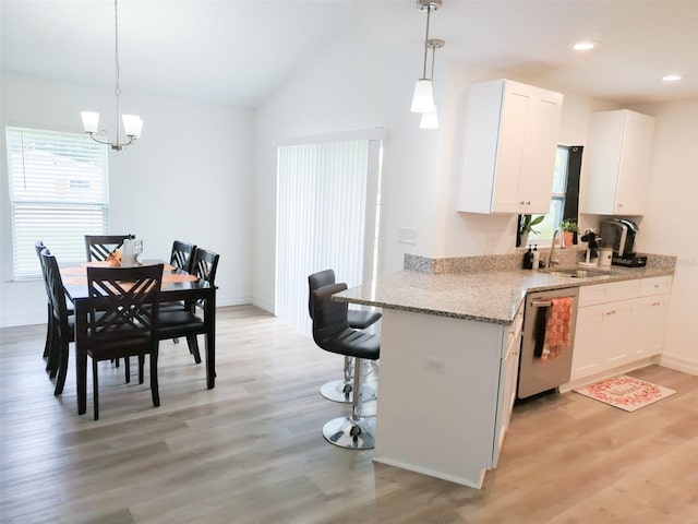 kitchen featuring pendant lighting, sink, stainless steel dishwasher, light hardwood / wood-style flooring, and white cabinetry