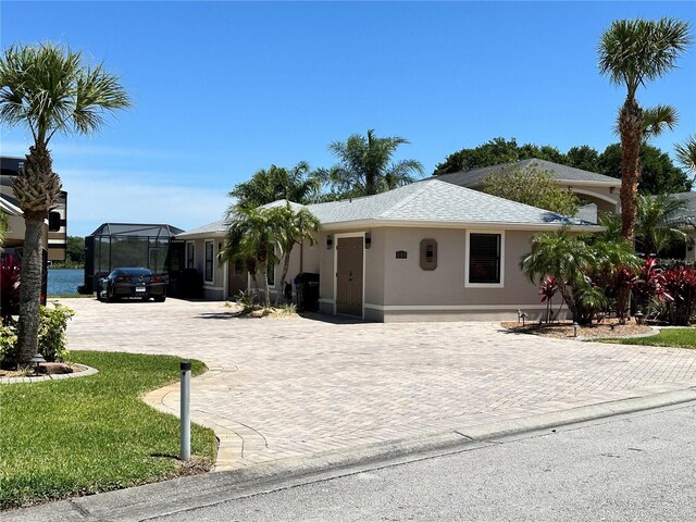 ranch-style house featuring curved driveway, a lanai, stucco siding, roof with shingles, and a front lawn
