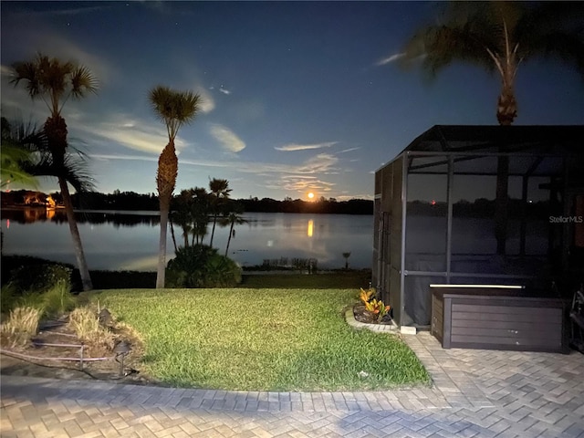 yard at dusk with glass enclosure and a water view