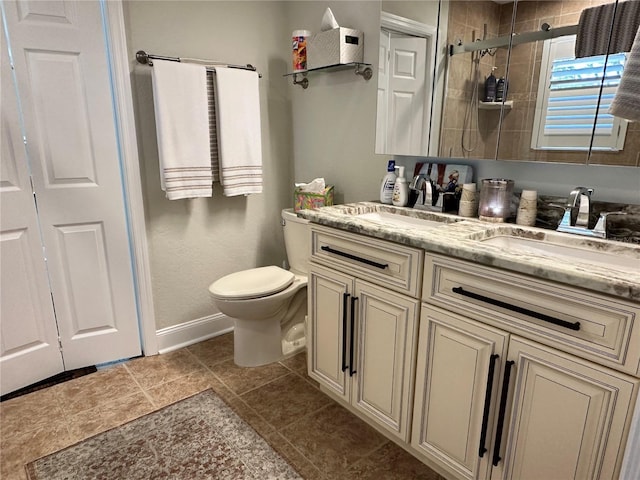 full bath featuring toilet, baseboards, a shower stall, a sink, and double vanity