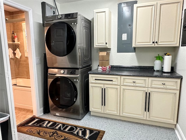 laundry area with stacked washing maching and dryer, electric panel, and cabinets